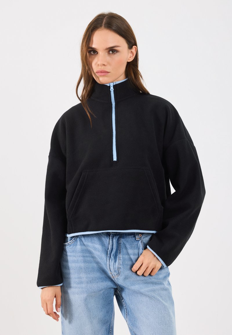 Hanorac din fleece negru cu guler înalt, închidere cu jumătate de fermoar și accente bleu deschis; dispune de o buzunar frontal și un design scurt.