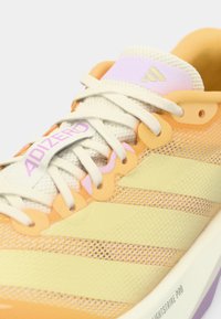 Lichte hardloopschoen in oranje en gele mesh, met een wit vetersysteem, paarse accenten en een gestructureerde zool. "ADIZERO" branding zichtbaar.