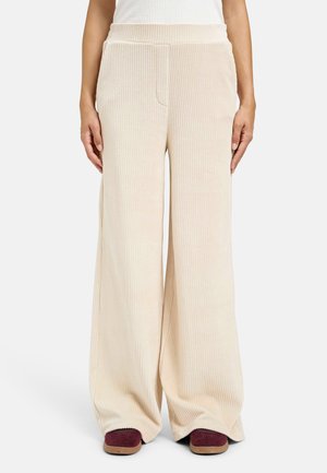 Wide-leg corduroy pants in cream, featuring vertical ribbing, an elastic waistband, and side pockets. Textured fabric with a soft finish.