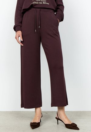 Woman wearing dark purple wide-leg pants and matching sweatshirt, paired with dark brown pointed slingback heels with a bow detail.