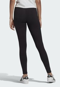 Svarta tights gjorda av stretchigt material, figurnära design, med hög midja. Matchas med vita sneakers med svarta accenter.