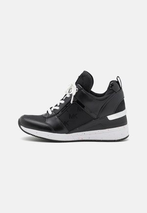 Czarny sportowy sneaker z białymi sznurówkami i białą, cętkowaną podeszwą, z subtelnym wzorem logo "MK" na bocznych panelach.