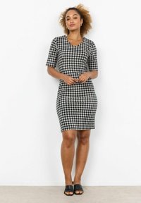 Musta-valkoinen houndstooth-kuosiset mekko, vartalonmyötäinen malli, lyhyet hihat, V-kaula-aukko, polvipituinen, yhdistettynä mustiin liukusandaaleihin.