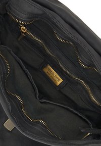 Interno di una borsa in pelle nera con cerniere dorate e fodera in tessuto. Presenta diversi scomparti con cerniere e un'etichetta del marchio.