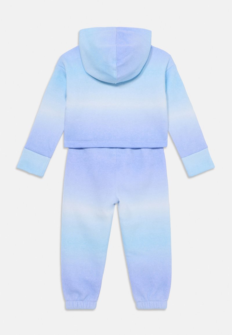 Vista trasera de un conjunto de sudadera y pantalón de chándal para niño pequeño, en un degradado de azul y morado, con puños elásticos y capucha en la sudadera.