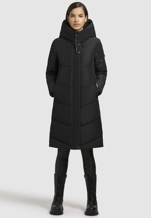 Black long puffer coat with a high collar, featuring prominent quilted sections and zipper closure, paired with black leather lace-up boots.