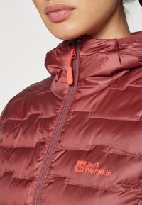 Maroon insulated jacket with a zip closure, featuring a hood, orange zipper pull, and a prominent logo on the chest. Textured fabric detail.