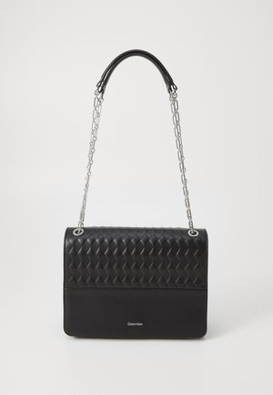 Μαύρη τσάντα με υφή πλεκτού στην κορυφή και λεία δερμάτινη βάση, διαθέτει αλυσίδα και λογότυπο.