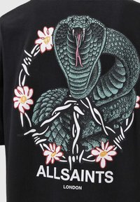 Μα�ύρο μπλουζάκι με γραφικό σχέδιο ενός πράσινου φιδιού που είναι τυλιγμένο ανάμεσα σε λευκά λουλούδια. Κείμενο "AllSaints London" σε λευκό χρώμα κάτω από το σχέδιο.