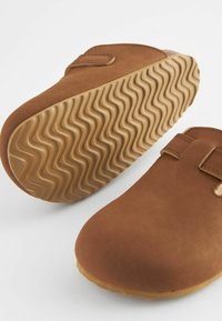 Brune slip-on sko lavet af glat ruskind med velcro-strop, der har en fleksibel gummisål med et bølget slidbane-mønster.