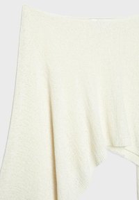 Mäkký, smotanovo biely pletený sveter s voľným strihom a vykrojenými ramenami, zobrazený na svetlom pozadí.