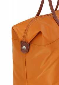 Oranje nylon tas met een gladde textuur, bruine leren handvatten en een zilveren ritsdetail. Het ontwerp heeft een zijvak en zachte randen.