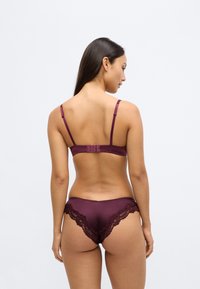 Lavandas krāsas apakšveļas komplekts ar gludu, zīdam līdzīgu krūšturi ar regulējamām lencēm un atbilstošām mežģīnēm rotātām biksītēm ar izsmalcinātām detaļām.