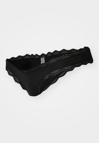 Black lace thong with scalloped edges, featuring a smooth fabric body and intricate lace detailing along the waistband.