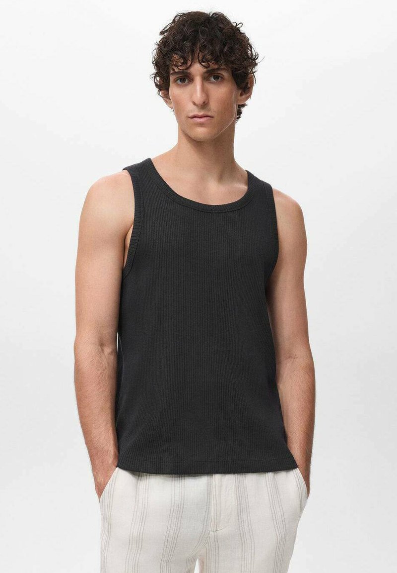 Top a canotta nera a coste con scollo rotondo, caratterizzato da un design senza maniche e una forma aderente, indossato con pantaloni a strisce di colore chiaro.