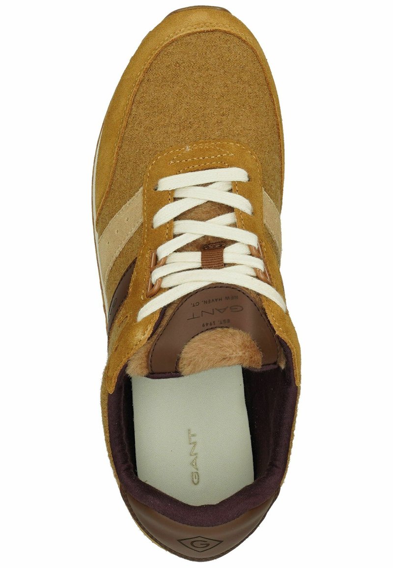 Tan suède sneaker met contrasterende beige strepen, witte veters en bruine leren accenten. Zachte voering zichtbaar rond het enkelgebied.