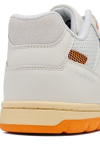 White leather sneaker with grey suede accents, orange mesh detailing, and textured gum rubber sole. "POWER PLAY" marked on the heel.