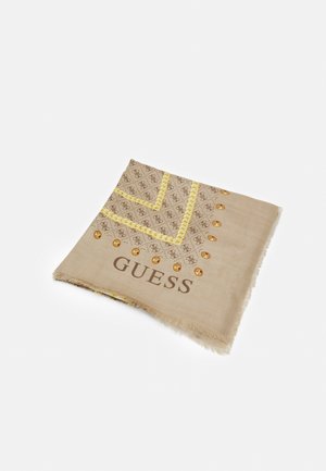 Beżowy szalik Guess z monogramem, żółtymi plecionymi detalami i złotymi ćwiekami wzdłuż jednego krawędzi na jednolitym białym tle.