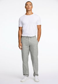Pantalons en lin gris clair avec une taille élastique, associés à un t-shirt ajusté à col rond blanc et des baskets blanches. Texture lisse, design décontracté.