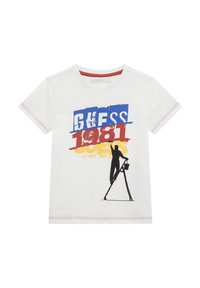 T-shirt bianca in cotone a maniche corte, con una stampa grafica audace in blu, rosso e giallo, e la silhouette di una figura su una scala.