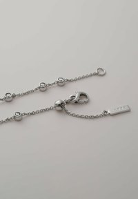 Silberarmband mit runden Gliedern, verziert mit kleinen klaren Steinen, ausgestattet mit einem Karabinerhaken und einem rechteckigen Anhänger, der mit "iette" graviert ist.