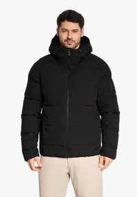 Veste matelassée noire avec un col haut et une capuche ajustable ; elle dispose d'une fermeture éclair à l'avant et de poches latérales ; design matelassé avec une texture lisse.