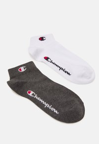 Dos pares de calcetines. Uno blanco con el logo negro de "Champion" y acento rojo, el otro gris oscuro con el logo blanco de "Champion". Tejido de mezcla de algodón.