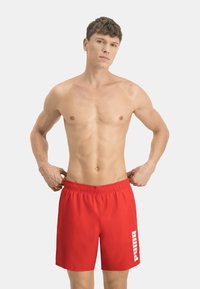 Bañador rojo con una cintura elástica, que presenta un logo blanco de "Puma" en el lateral, confeccionado en una tela ligera y suave.