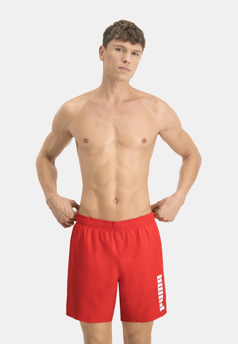 Bañador rojo con una cintura elástica, que presenta un logo blanco de "Puma" en el lateral, confeccionado en una tela ligera y suave.