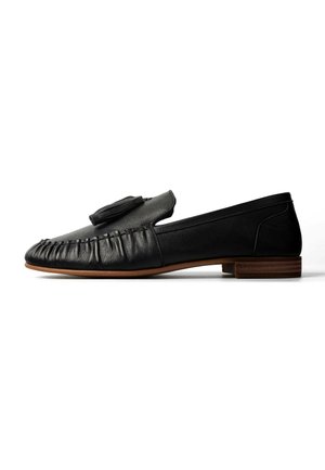 Zwarte leren loafer met tassel-detail, mocassinnaaistijl en lage houten hak, zijaanzicht op witte achtergrond.