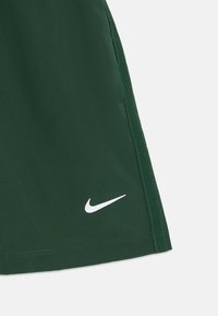 Pantalones cortos deportivos verdes hechos de una tela ligera, con un logo blanco de Nike en la parte inferior derecha y detalles de costura lateral en contraste.
