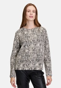 Sweter o fakturze w czerni i bieli z liściastym wzorem. Długie rękawy, okrągły dekolt i lekko luźny krój.
