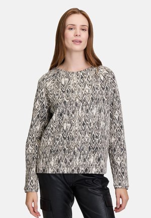 Pull-over texturé en noir et blanc avec un motif en forme de feuille. Manches longues, col rond et coupe légèrement ample.