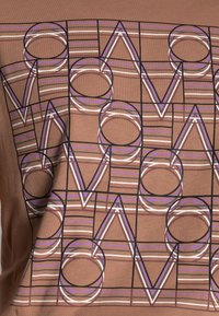 Una tela marrón presenta un diseño geométrico con letras "V" y "O" superpuestas, contorneadas en negro y acentuadas con líneas moradas y blancas.