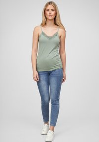 Mintgrønn camiskjorte med blondekant ved utringingen, parret med blå skinny jeans og hvite joggesko. Glatt stoff og tettsittende design.