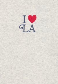 T-shirt gris avec du texte brodé "J ♥ LA" avec un cœur rouge et des lettres bleu marine. Tissu doux avec une texture lisse.