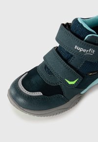 Dziecięce granatowe i turkusowe trampki z dwiema paskami na rzep, szarym podbiciem, zielonym akcentem oraz oddychającą siateczką wewnętrzną.