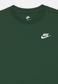 Tamnozeleni Nike majica s bijelim Nike logom i swooshom na gornjem lijevom prsima i oznakom unutar vrata.