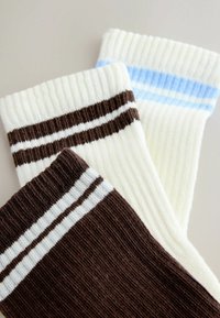 Trei perechi de șosete cu dungi, una maro cu dungi albe, una crem cu dungi maro închis și una crem cu dungi albastru deschis.