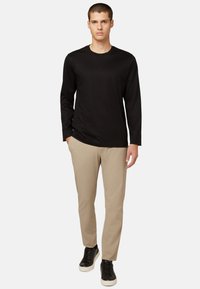 Mustas pikad varrukad särk, beež slim-fit püksid ja mustad tossud. Lihtne disain, sujuv tekstuur ja minimalistlikud aktsendid.