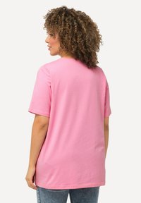 T-shirt di cotone rosa con maniche corte, vestibilità comoda, scollatura rotonda e una texture liscia. Il retro è semplice, senza motivi o dettagli.