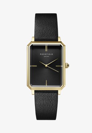 Montre avec un boîtier octogonal en or et un bracelet en cuir noir texturé. Le cadran noir présente des motifs concentriques ainsi que des index et aiguilles dorés.