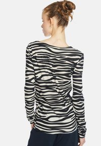 Langarmshirt mit einem schwarz-weißen Zebra-Streifenmuster, aus weichem Stoff gefertigt, mit einem leicht lockeren Schnitt und rundem Halsausschnitt.