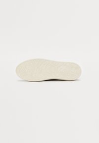 Sko såle i off-white gummi, med teksturerte bølgemønstre for grep. Rent design uten synlig merkevare eller tilleggsmotiver.