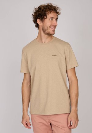 T-shirt en coton beige à manches courtes et à encolure ronde. Présente un logo brodé subtil sur la poitrine. Texture douce.
