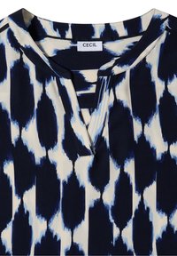 Col et encolure d'un chemisier à motif bleu et blanc avec une fente en forme de trou de serrure et une étiquette de marque CECIL cousue.