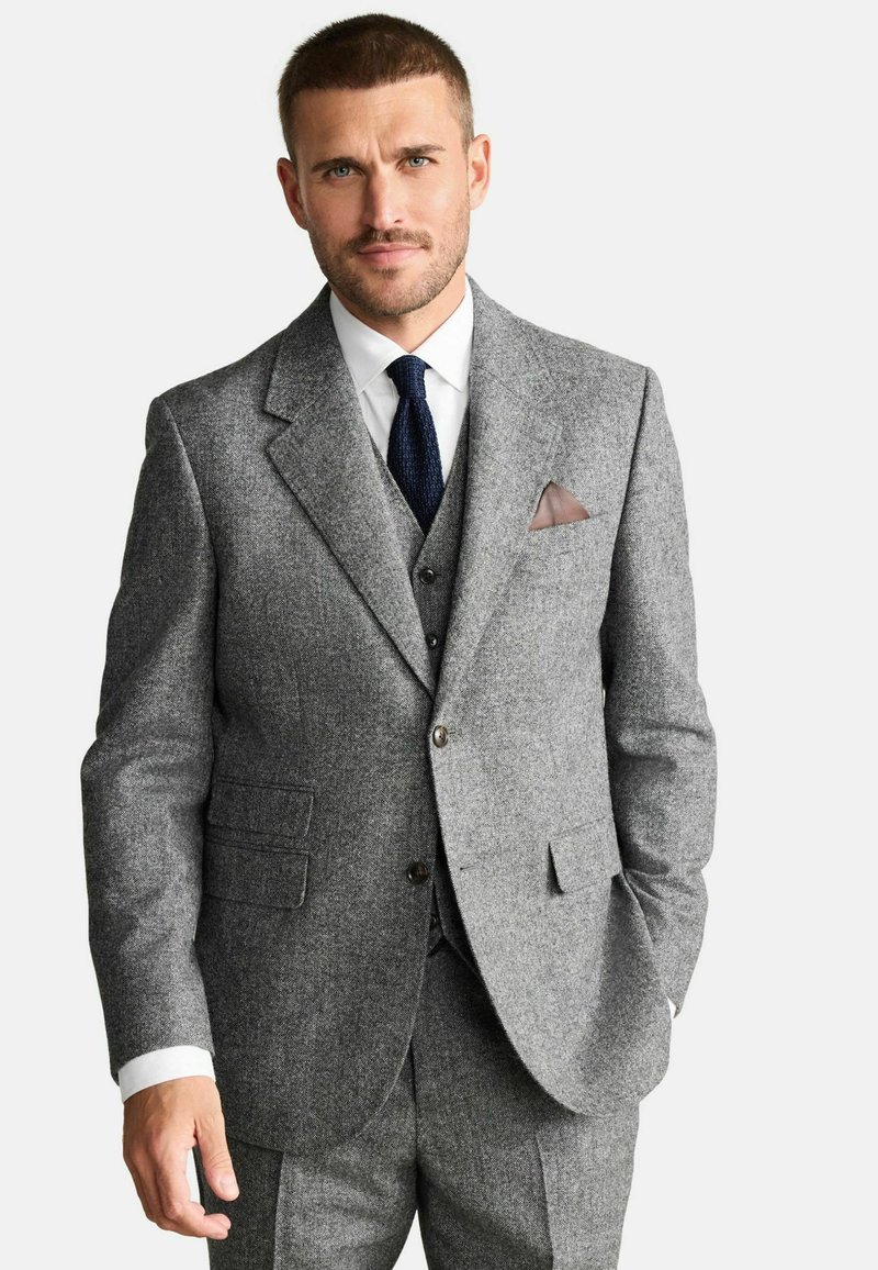 Gray wool suit with a structured jacket, matching vest, and tailored trousers. Features notch lapels, a white dress shirt, and a textured tie.