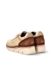 Zapatos de ante beige y marrón con punta redondeada, diseño de cordones, collar acolchado y suela gruesa color crema. Textura suave y colores contrastantes.
