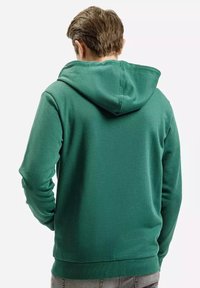 Zielona bluza z kapturem o teksturowanym wykończeniu i ściągaczami u rękawów. Posiada konstrukcję z szwem na plecach i luźny fason.