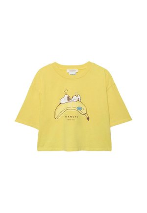 Žlté krátke tričko so Snoopym ležiacim na veľkej banánovej grafike a textom "PEANUTS SINCE 1950" pod ňou.